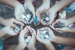Group of children holding money in hands in the circle together