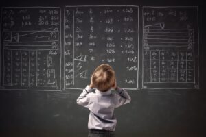A photo of a small child in front of a blackboard full of equations.