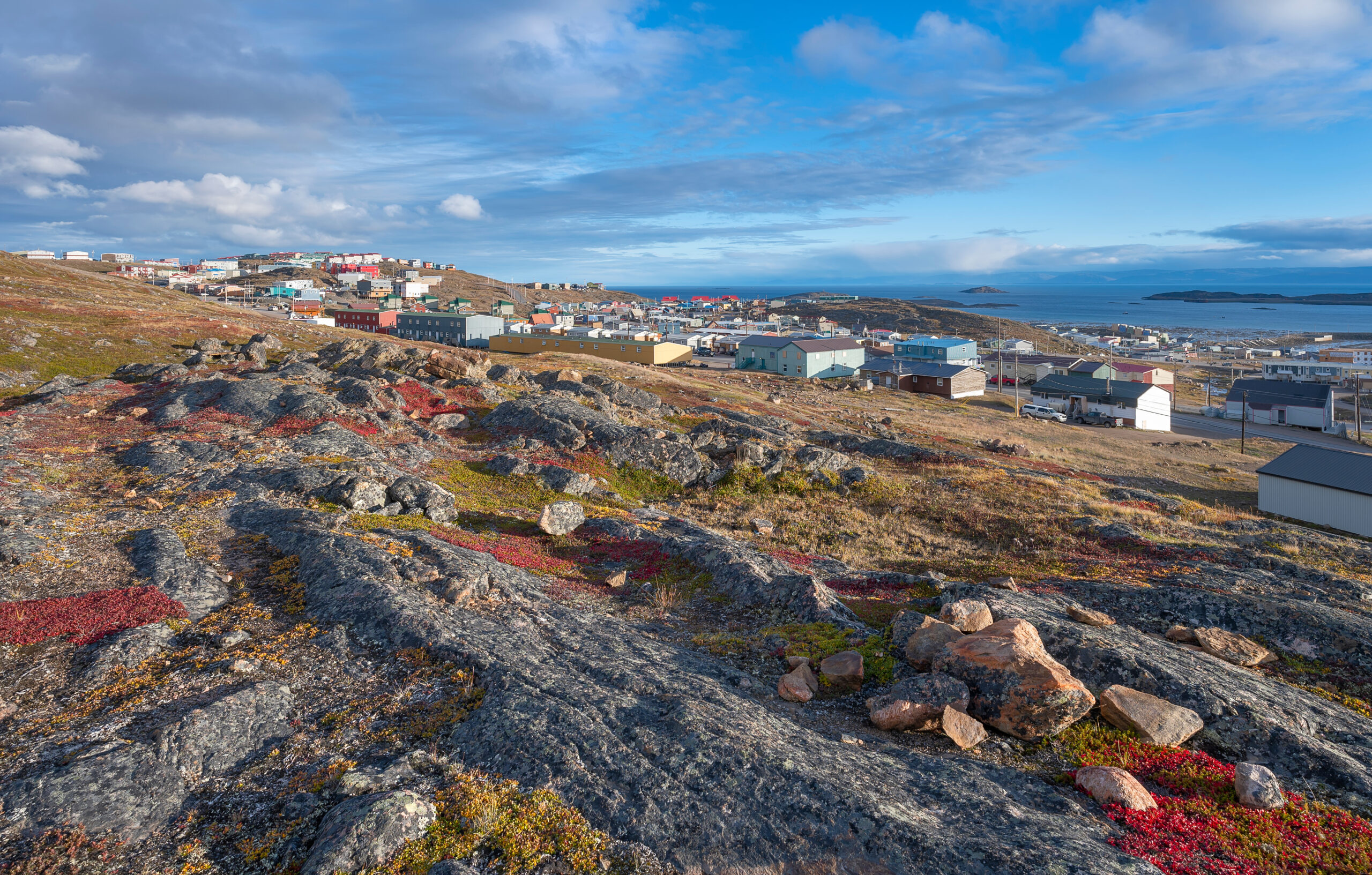 Overview of the colourful houses of the city of Iqaluit with the Arctic Ocean harbour in the distance