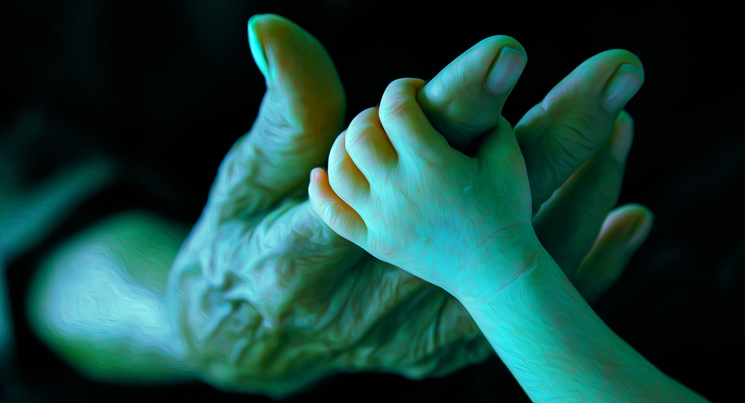 An older person's hand and with a baby's hand holding the index finger