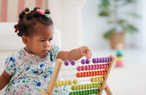 Cute baby girl playing with a colourful abacus toy.