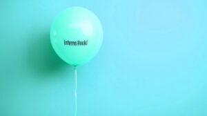 A cyan coloured balloon on a cyan coloured wall. The ballon has text that says "Interns Rock!".